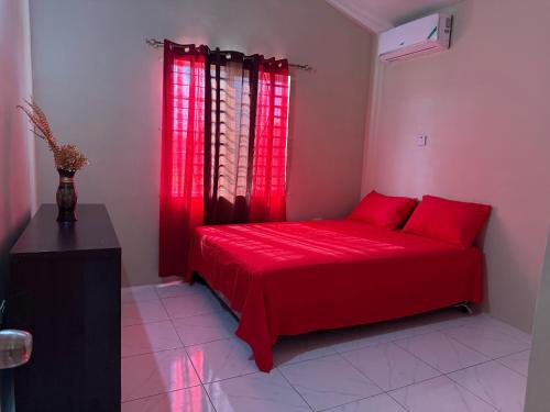 a red bed in a room with red curtains at Finest Accommodation Phoenix Prk Village 1,Phase 4 lot 1347, 26 Sheawater Ave in Portmore