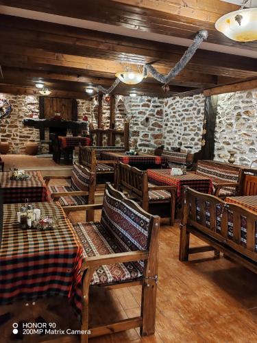 a restaurant with tables and chairs and a stone wall at Парк - Хотел Макензен in Melnik
