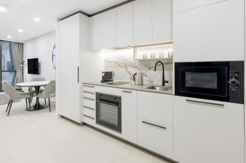 a white kitchen with a sink and a microwave at Meriton Suites Canberra in Canberra