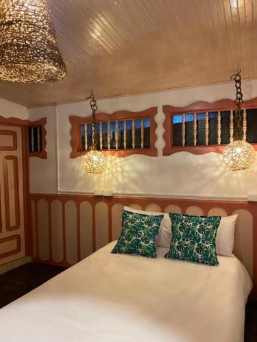 a bedroom with a bed with two green pillows at Mahalo Hostel in Salento