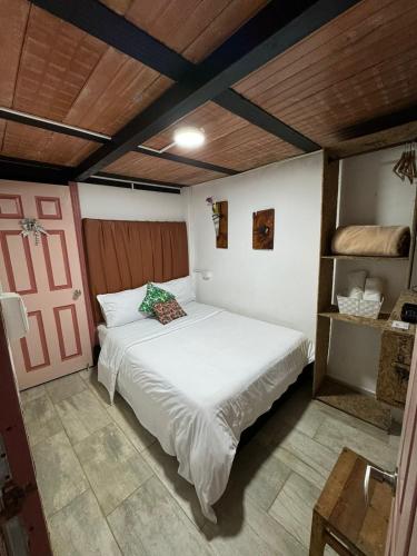 a bedroom with a white bed and a wooden ceiling at Mahalo Hostel in Salento