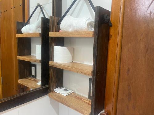 a bathroom cabinet with wooden shelves and a mirror at Hostería CASA SAN LUIS in Mindo