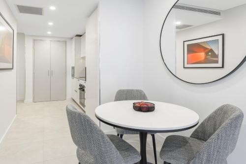 a dining room with a white table and chairs and a mirror at Meriton Suites Canberra in Canberra