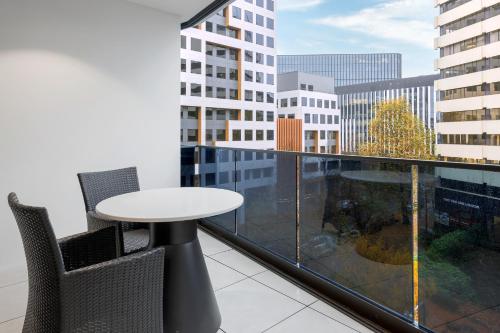 a table and chairs on a balcony with a view of a city at Meriton Suites Canberra in Canberra