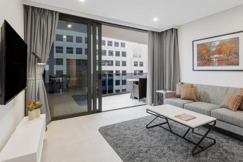 a living room with a couch and a table at Meriton Suites Canberra in Canberra