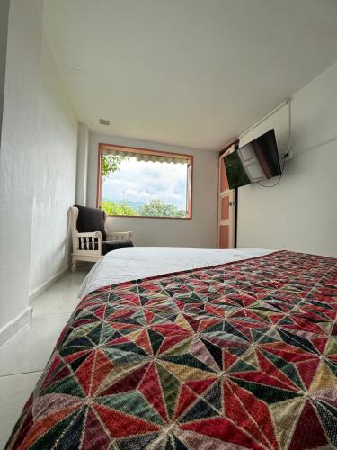 a bedroom with a bed with a quilt on it at Mahalo Hostel in Salento