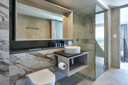 a bathroom with a sink and a toilet and a mirror at Meriton Suites Canberra in Canberra