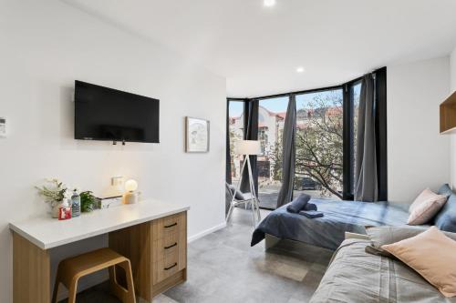 a bedroom with a bed and a desk and a tv at Cozy Stays - Private Rooms in Adelaide CBD with Shared Facilities in Adelaide