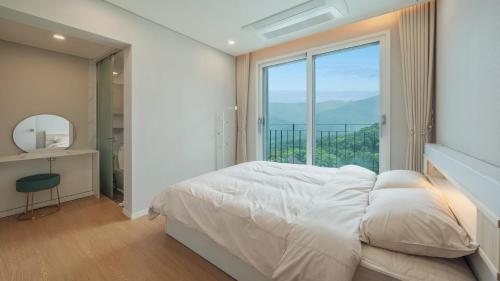 une chambre avec un lit et une grande fenêtre dans l'établissement Gapyeong staysumok pool villa pension, à Gapyeong