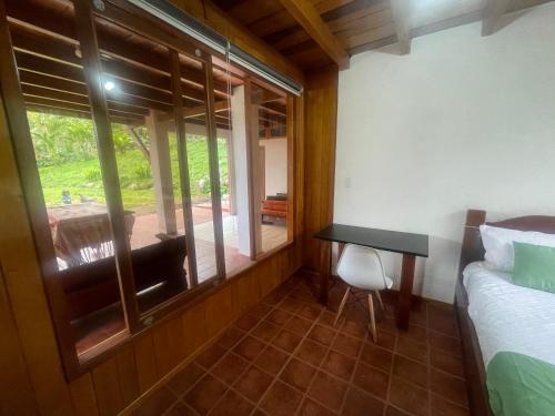a bedroom with a bed and a desk and a window at Hostería CASA SAN LUIS in Mindo