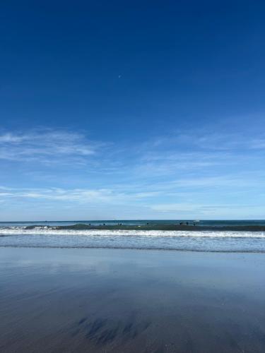 a beach with waves in the ocean and a blue sky at Sand Castles Beachfront Resort in Zambales