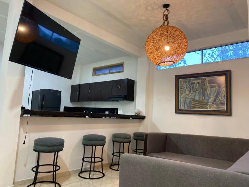 a living room with a couch and bar with stools at Mahalo Hostel in Salento