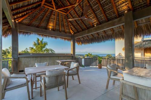 a patio with tables and chairs and a view of the ocean at Casa Los Dichos in Brisas de Zicatela