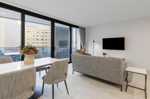 a living room with a table and chairs and a television at Meriton Suites Canberra in Canberra