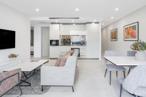a living room with tables and chairs and a kitchen at Meriton Suites Canberra in Canberra