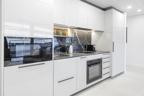 a kitchen with white cabinets and stainless steel appliances at Meriton Suites Canberra in Canberra