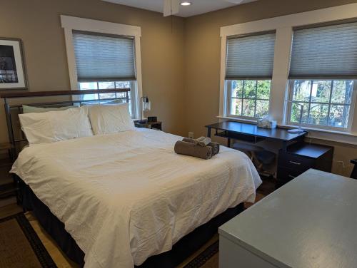 a bedroom with a bed and a desk and two windows at Back Alley Apartment, Walk Downtown And Duke in Durham