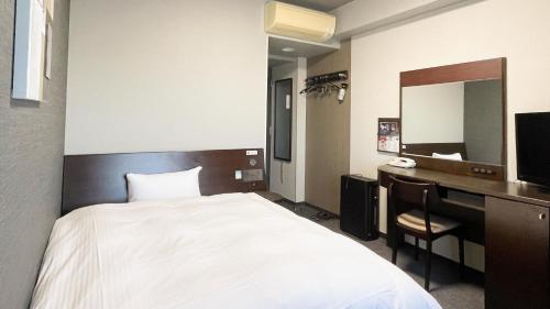 a bedroom with a bed and a desk and a mirror at Hotel Route-Inn Mitsukaido Ekimae in Joso