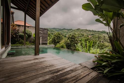 a view of a pool from a house with a wooden deck at Abinawa Hill in Lovina