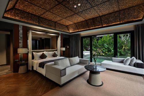 a bedroom with a bed and a couch and windows at Ayatara Resort Ubud in Payangan