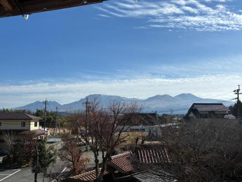 a view of a town with mountains in the background at Tabinoyado Asonoyu in Aso