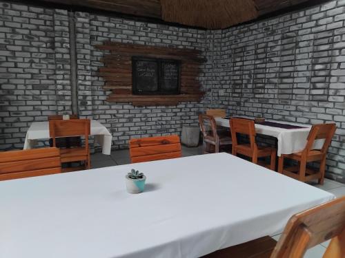une salle à manger avec des tables et des chaises blanches dans l'établissement Corner House Cottages, à Groutfontein