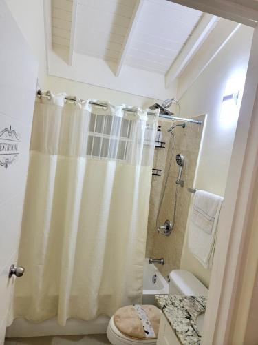 a bathroom with a shower curtain and a toilet at The Surada Bay 2 bedrooms in Old Harbour