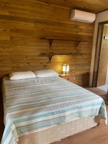 a bedroom with a bed with a wooden wall at Chalé Aracuã 2 in Torres