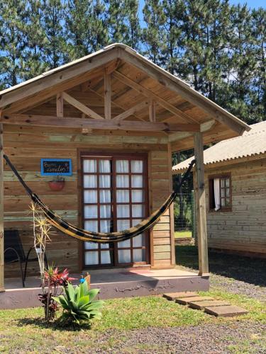 a log cabin with a hammock in front of it at Chalé Aracuã 2 in Torres