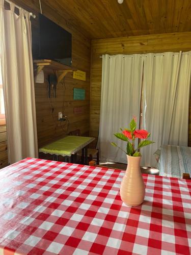 a vase with flowers on a red and white checkered table at Chalé Aracuã 2 in Torres