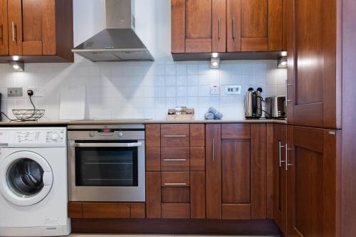 a kitchen with wooden cabinets and a washing machine at Aphrodite Premium Apartments I in Kouklia
