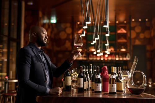 a man standing at a bar holding a glass of wine at Cinnamon Life at City of Dreams in Colombo