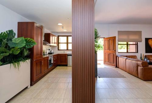 a kitchen with wooden cabinets and a living room at Aphrodite Premium Apartments I in Kouklia