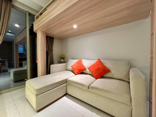 a living room with a couch with two orange pillows at Gold Coast Apartment PIK Luxury Sea View by stay with E in Jakarta