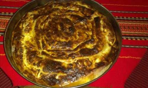 een pizza in een pan op een rode tafel bij Dedovite Kashti in Stefanovo