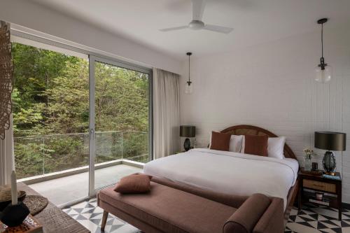 a bedroom with a bed and a large window at La Olalian 2 & 3 BHK Designer Villas Near Anjuna Beach with Private Pool & Sun Deck & Garden in Anjuna
