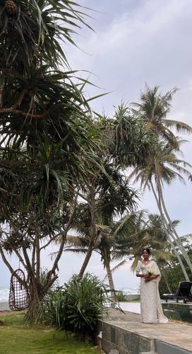a woman standing in front of some palm trees at Saltasia Boutique Beach Villa in Mirissa