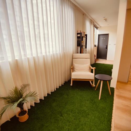 a living room with a chair and green carpet at Fooyee Hotel - Yonghe in Yonghe