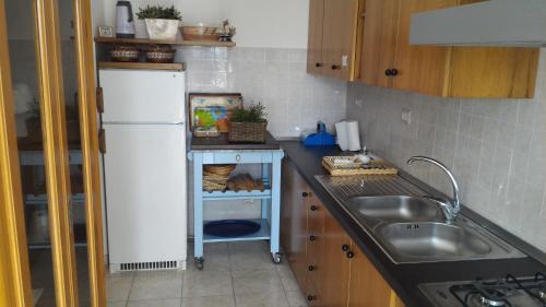La cuisine est équipée d'un réfrigérateur blanc et d'un évier. dans l'établissement B&B Gelsimori, à Otrante