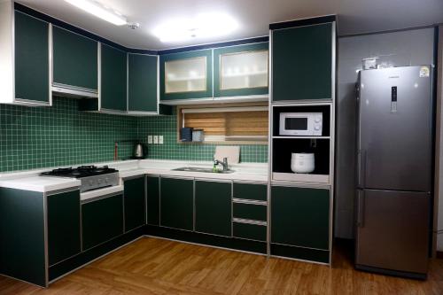 eine Küche mit grünen Schränken und einem Kühlschrank in der Unterkunft tebaz in Jeju-do