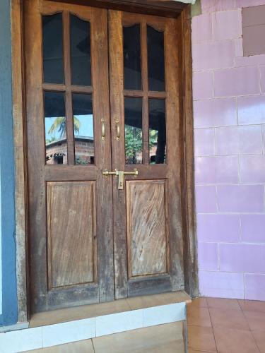an old wooden door in a pink wall at Murdeshwar Coastal Comfort in Māvalli