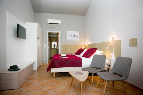 a bedroom with a bed and two chairs and a tv at Le Relais Des Trois Mas in Collioure
