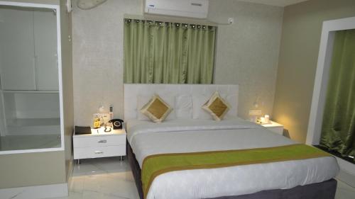 a bedroom with a large white bed with green accents at Geetanjali International in Deoghar