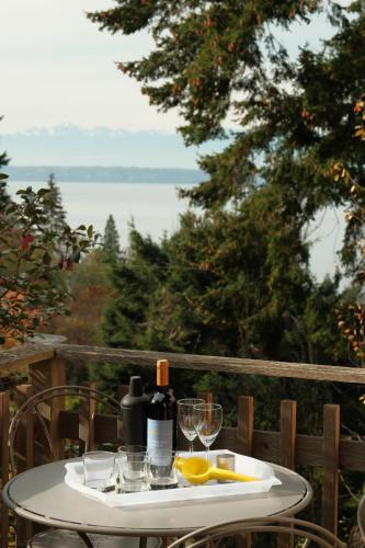 a white table with wine bottles and glasses on it at Water Mtn Views, Forest Walk To Beach! in Clinton