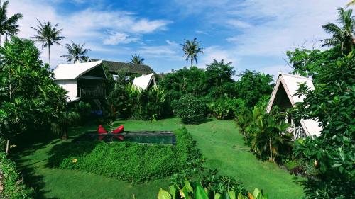 a garden with green grass and houses and trees at Beachfields Bungalows in Balian