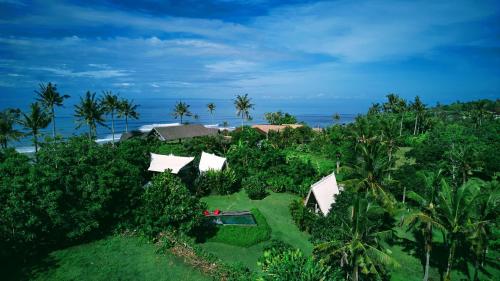 an aerial view of a resort with trees and the ocean at Beachfields Bungalows in Balian