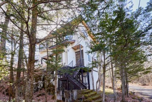 a white house with a staircase in the trees at rinne 2nd living Kitakaruizawa Forest in Tsumagoi