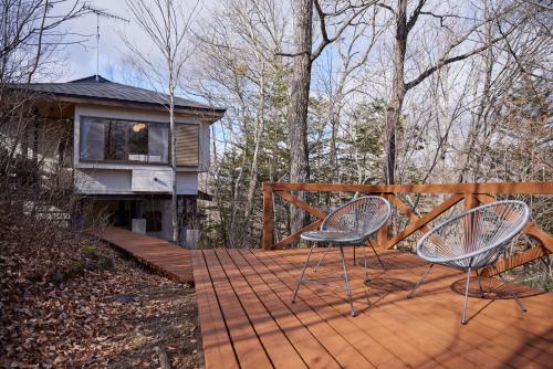 a pair of chairs sitting on a wooden deck at rinne 2nd living Kitakaruizawa Forest in Tsumagoi