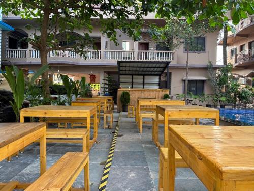 a row of wooden tables and benches in a courtyard at Serendipity Goa - Apartments and Cafe in Arambol