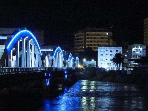 a bridge with blue lights over a river at night at Ano Bom Palace Hotel in Barra Mansa